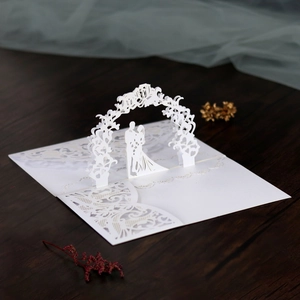 Macro shot of laser-cut 3D wedding card with floral arch and couple silhouette