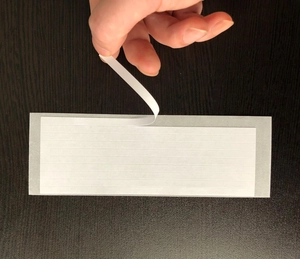 Detail showing hand peeling white adhesive wedding cone tapes on dark surface