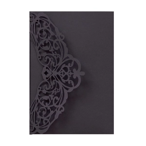 Macro detail of intricate laser-cut baroque patterns on a black invitation envelope
