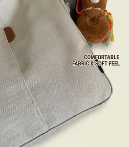 Détail du sac seau en toile beige avec logo en cuir et pendentif alpaga en peluche brune