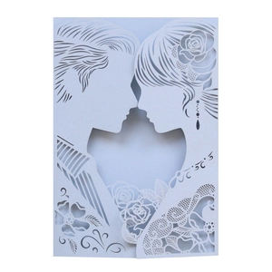 Detail of laser-cut white lace wedding invitation with romantic couple and rose pattern