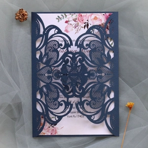 Detail of laser-cut navy blue lace wedding invitation with floral printed insert card