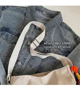 Détail de la bandoulière réglable et du pompon tissé coloré sur le sac seau en toile