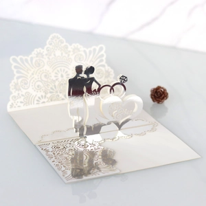 Macro view of 3D laser cut wedding card showing silver Mr & Mrs silhouette and rings