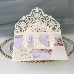 Macro detail of laser-cut 3D wedding invitation with floral insert on gold-rimmed tray