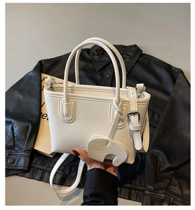 Close-up of white lychee pattern leather bag featuring a decorative elephant charm detail