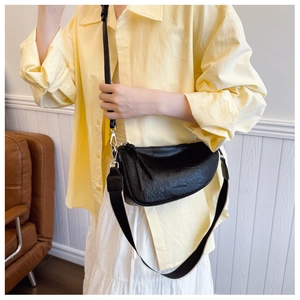 Detail van de zwarte lederen halve maan crossbody tas met brede zwart-wit geweven riem