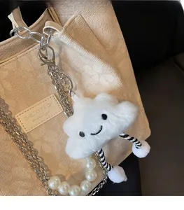 Detail of white plush smiley cloud charm with striped rope legs on a tote bag