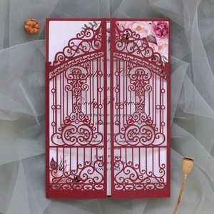 Close-up of laser-cut burgundy wedding invitation with elegant gate design and floral insert