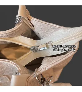 Close-up of smooth silver metal zipper and textured fabric detail on a beige tote bag