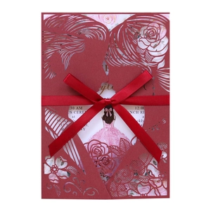 Detail of laser cut burgundy wedding invitation with ribbon bow and floral illustration