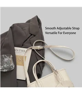 Close-up of litchi pattern leather texture and adjustable shoulder strap on white handbag