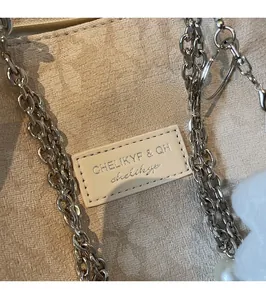 Detailed macro view of jacquard fabric tote with embossed leather logo and silver metal chain