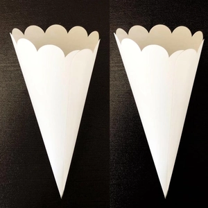 White scalloped edge paper cones for wedding confetti or party treats, set on black background