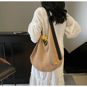 Detail of hand-woven beige tote bag featuring floral crochet and black leather strap
