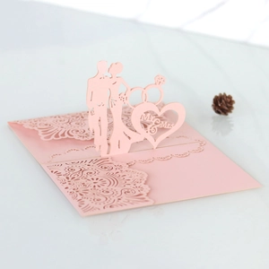 Macro detail of laser-cut pink 3D wedding card with Mr & Mrs text and ring patterns