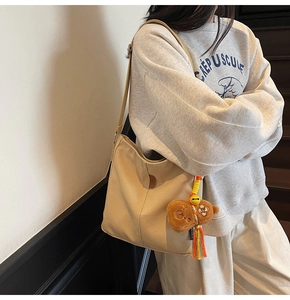 Détail du sac seau en toile avec écusson en cuir marron et porte-clé ours adorable