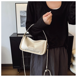 Detail of a minimalist beige leather pillow bag with silver chain and CEHEKA logo
