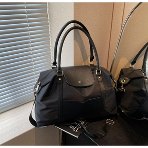 Vue détaillée du grand cabas noir en nylon avec rabat en cuir et bandoulière réglable