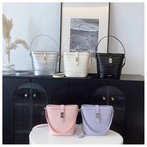 Detail view of crocodile textured bucket bags in five colors with metal buckles