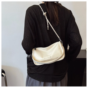 Detailed close-up of cream white crossbody bag with golden chain and metal ball decoration