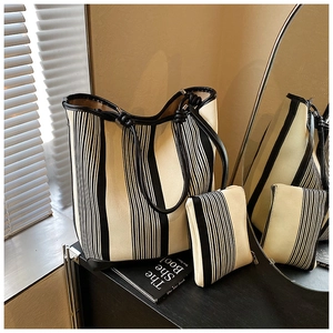Detail view of striped canvas tote bag and matching small pouch with black leather handles