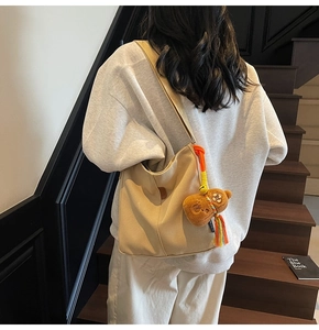 Sac seau en toile beige porté à l'épaule avec détail de charmant ours en peluche