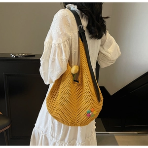 Detail of yellow hollow knit tote bag with floral patch and black leather strap