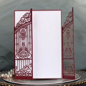 Detail of laser-cut wedding invitation with intricate gate patterns and pearl decor