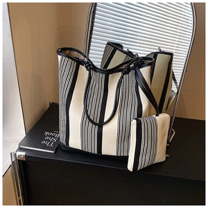Detail of black and white striped canvas tote bag set with leather trim and knotted handle