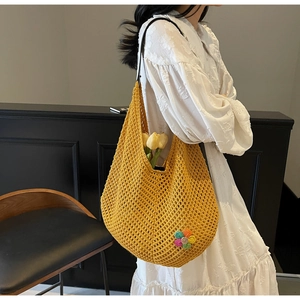 Detail of yellow hollow crochet tote bag with colorful floral embroidery and black cord strap