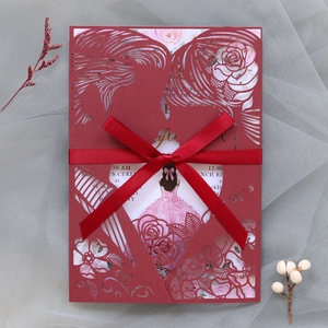 Detail of dark red laser-cut invitation with couple silhouette and red satin ribbon bow