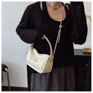 Detail of cream white leather crescent bag with silver chain and sphere charm