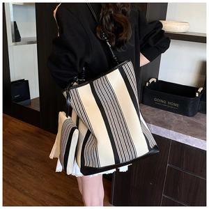 Detail of a large black and white striped canvas tote bag with leather straps on a model