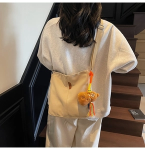 Détail du sac seau en toile avec charm ours et pompon sur la bandoulière