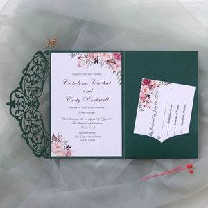Detail of laser-cut wedding invitation set with floral inserts and dark green cover