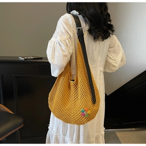 Detail of yellow knit crochet tote bag with leather strap and colorful flower charm