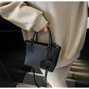 Detail of black lychee grain leather mini handbag with cute elephant charm accessory