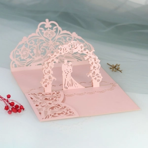 Macro shot of 3D laser-cut wedding invitation featuring a couple silhouette in pink