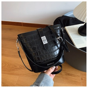Detail of black crocodile embossed bucket bag featuring a silver metal twist lock closure