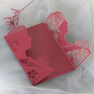 Detail of red laser-cut wedding invitation featuring rose patterns and a romantic silhouette