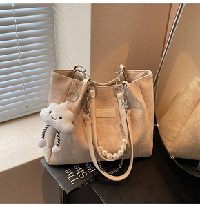 Detail of cream tote bag with pearl chain, cloud charm, and soft window light shadows