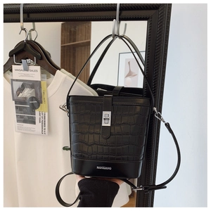 Detail of black crocodile texture bucket bag with silver twist lock and brand logo
