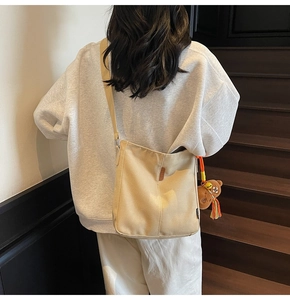 Détail du sac seau en toile beige avec bandoulière large et breloque ours marron