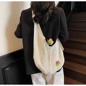 Close-up of white crochet tote bag with colorful flower embroidery on a wooden staircase