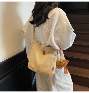Détail du sac seau en toile avec étiquette en cuir DZSG et charm d'ours brun mignon