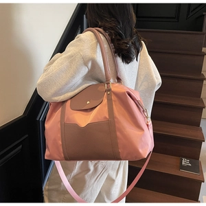Grand sac fourre-tout en nylon rose et cuir marron porté à l'épaule dans un escalier