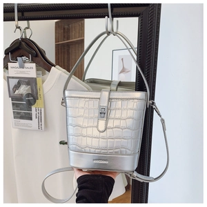 Detail of silver crocodile-embossed bucket bag showing metallic finish and structured handle