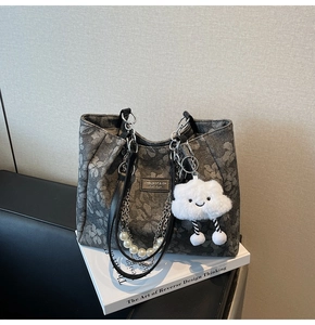 Detail of dark grey floral tote bag with pearl chain, metal strap and plush cloud charm