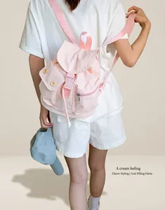Detail of pink canvas mini backpack with buckle flap and yellow button accents on a model
